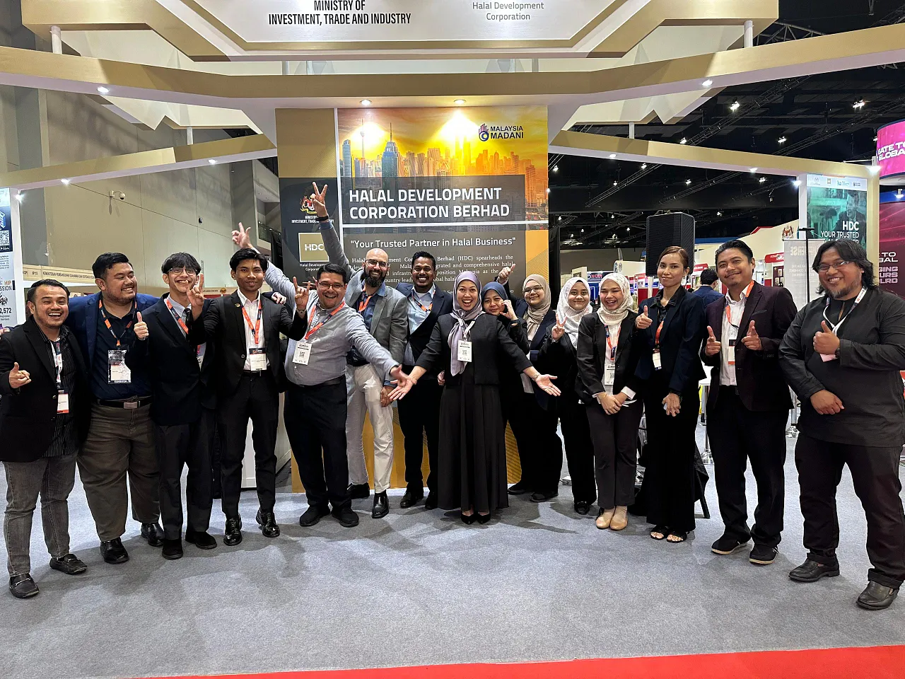 The joint GoHalal and Halal Development Corporation Berhad (HDC) teams standing together at the MIHAS trade exhibition booth.